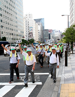 （炎天下の中、シュプレヒコールをあげながら、自民党会館から日比谷公園まで、各省庁が立ち並ぶ街頭をデモ行進）